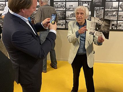 Kleurenfoto waarop te zien is dat burgemeester Hein van der Loo een foto maakt van Bob Friedländer. Foto: Stadsarchief Almere
